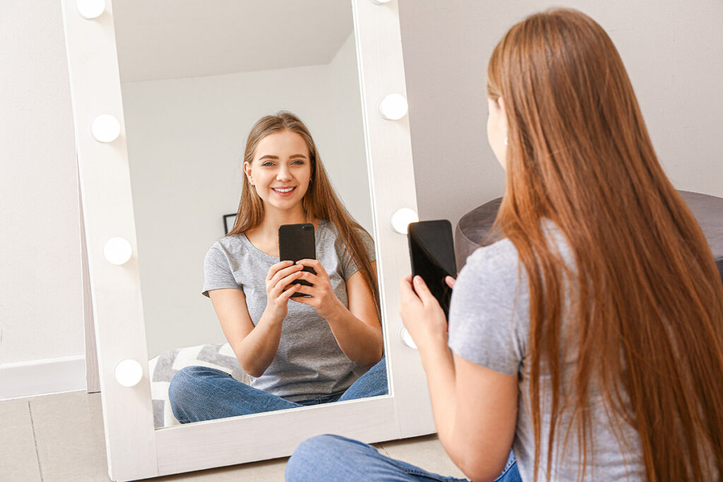 young woman taking selfie in front of mirror at home